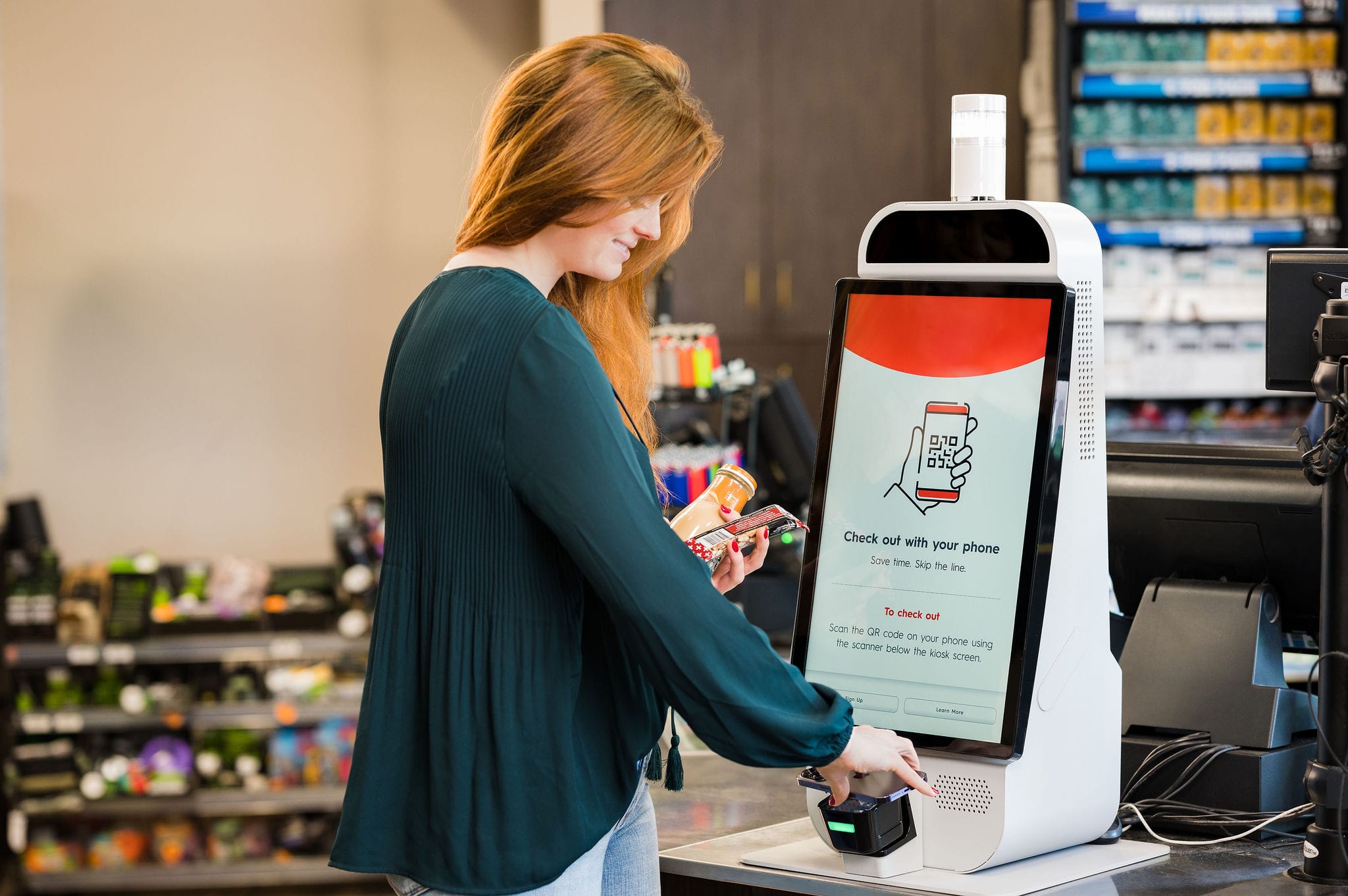 Mapco store woman scanning phone at self checkout